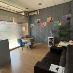 Foto del interior de una sala de recepción con un sofá, mesa con dos sillas y mesa infantil con juegos en la esquina